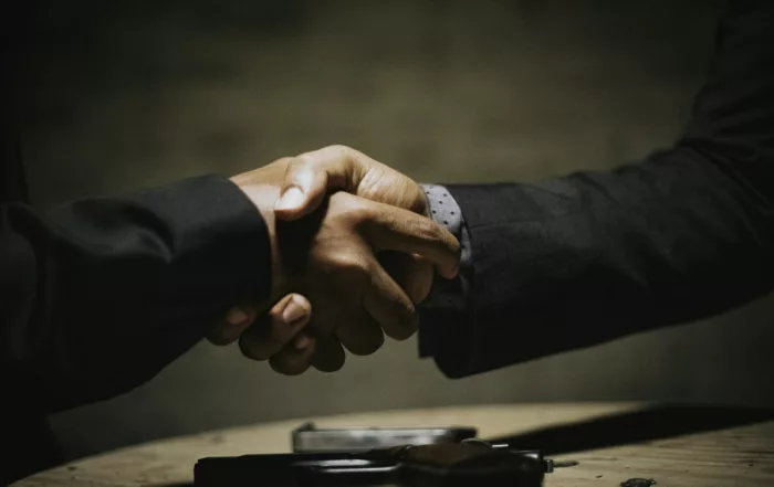Dos profesionales se estrechan la mano sobre una mesa de madera tras cerrar un acuerdo