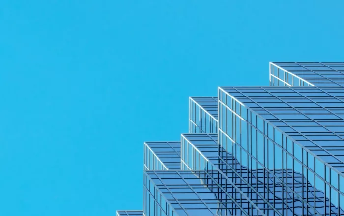 Edificio moderno de cristal con fachada escalonada reflejando un cielo azul