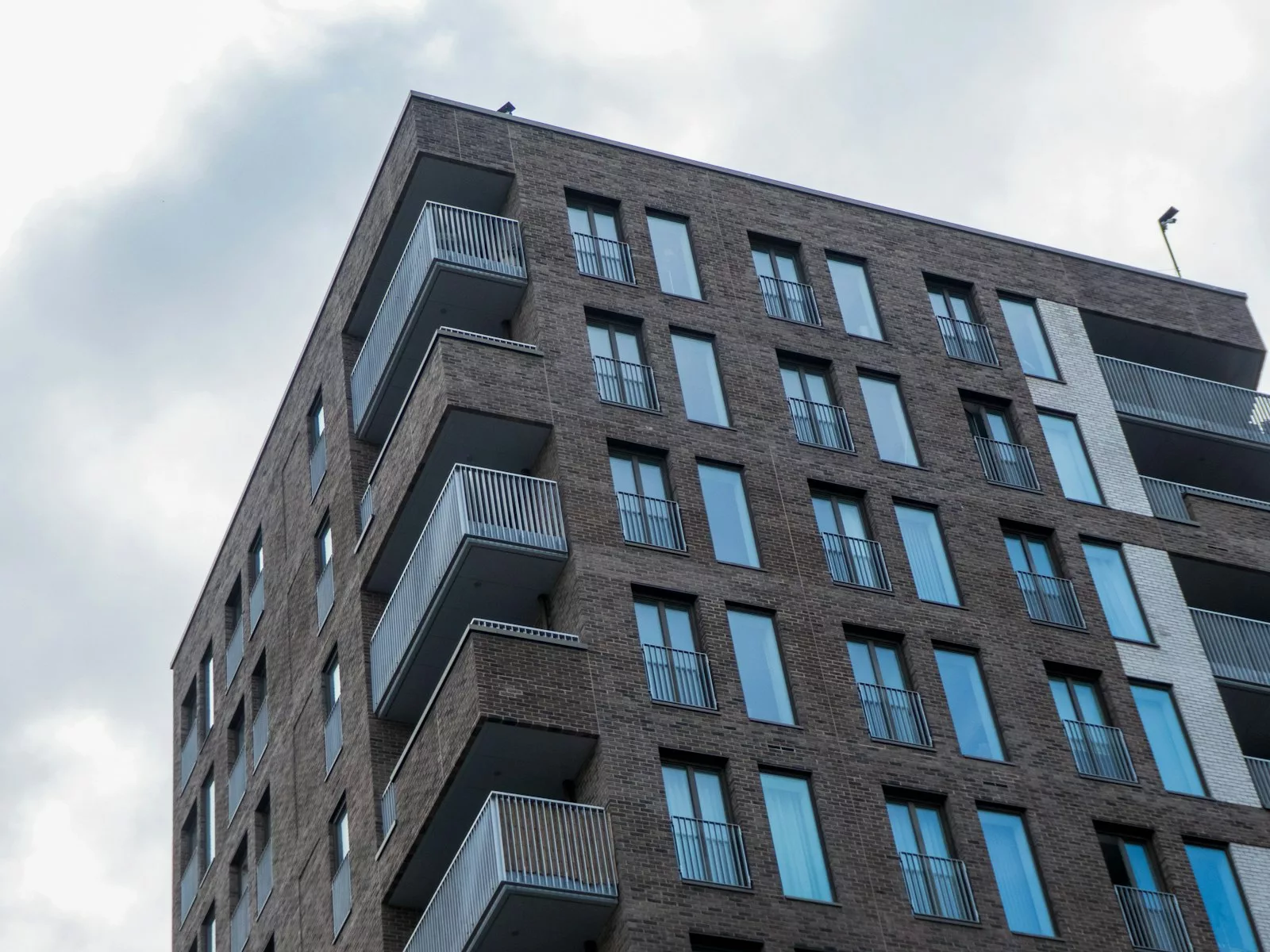 Edificio de viviendas de ladrillo con balcones, activo real que respalda alternativas al crowdlending inmobiliario