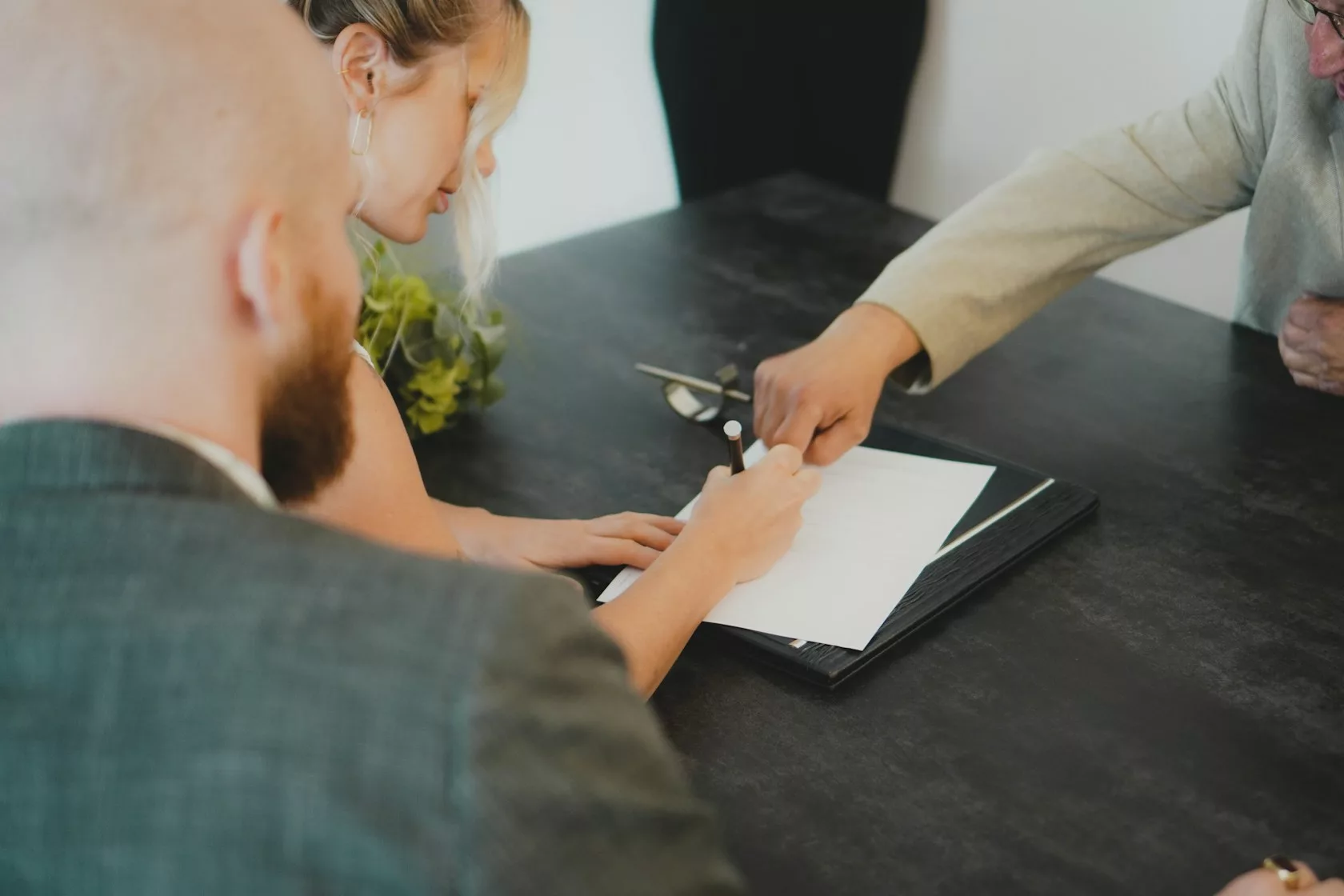 Pareja firmando documentos en un escritorio: riesgos legales de invertir en NPL